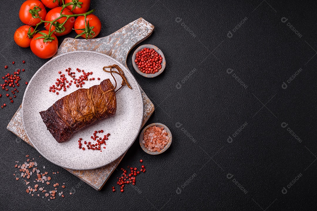 Delicioso peito de frango de carne defumada com sal, especiarias e ervas sobre um fundo escuro de concreto