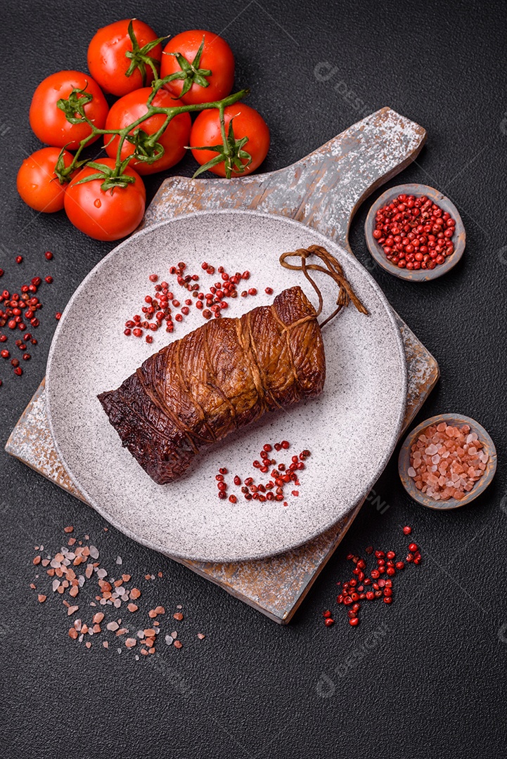 Delicioso peito de frango de carne defumada com sal, especiarias e ervas sobre um fundo escuro de concreto