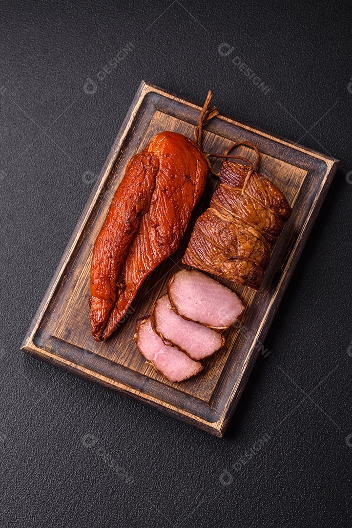 Delicioso peito de frango de carne defumada com sal, especiarias e ervas sobre um fundo escuro de concreto