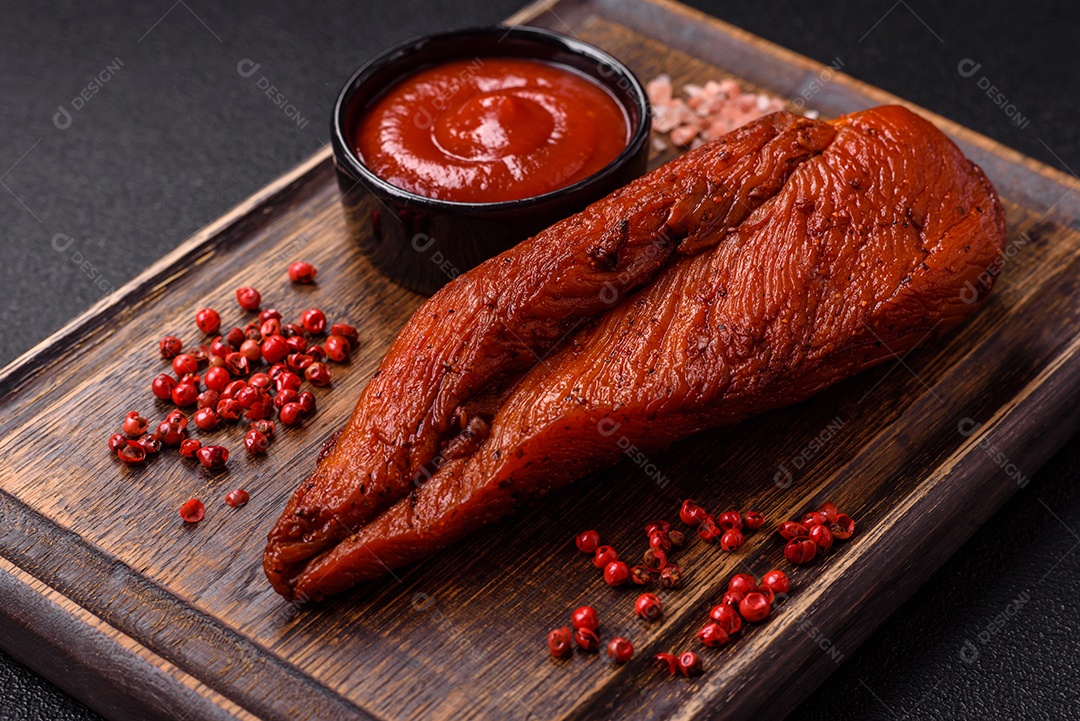 Delicioso peito de frango de carne defumada com sal, especiarias e ervas sobre um fundo escuro de concreto