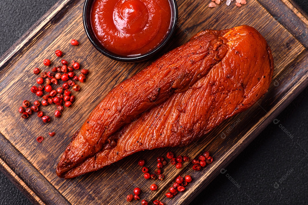 Delicioso peito de frango de carne defumada com sal, especiarias e ervas sobre um fundo escuro de concreto