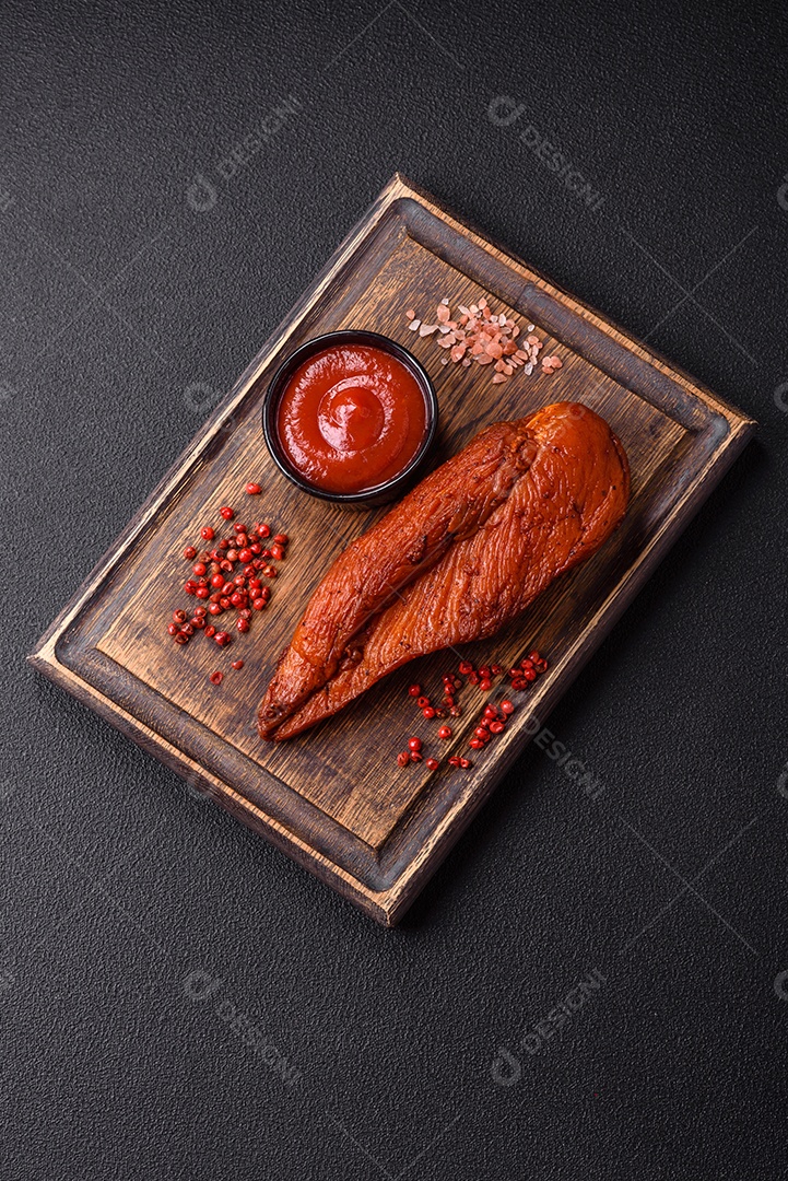 Delicioso peito de frango de carne defumada com sal, especiarias e ervas sobre um fundo escuro de concreto