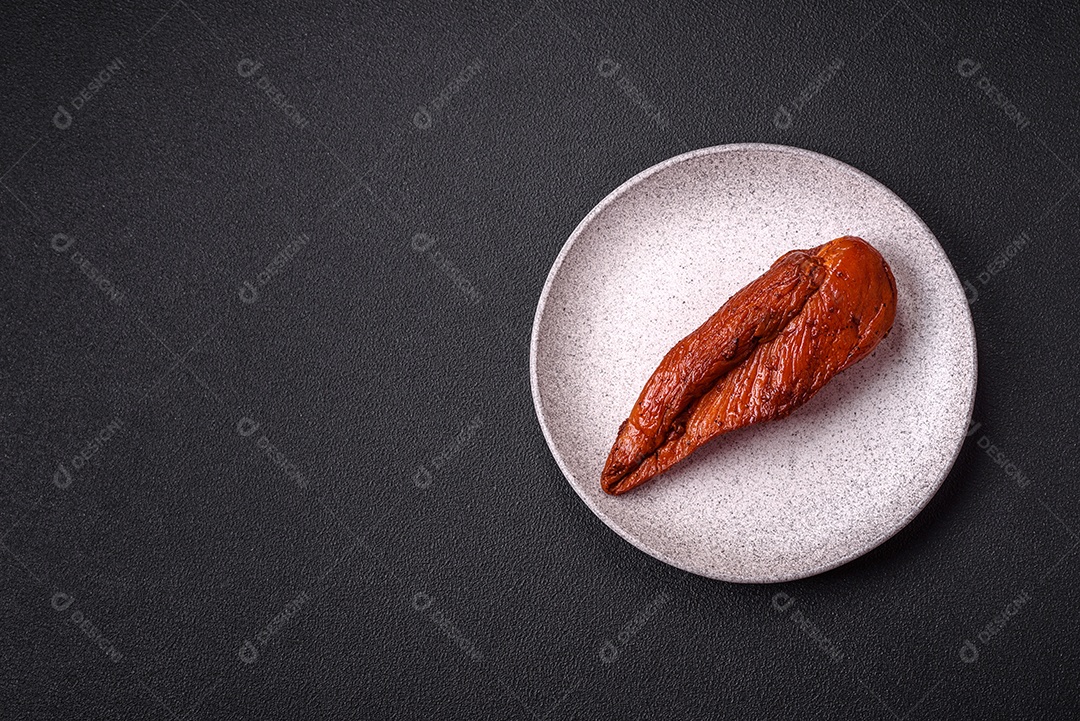 Delicioso peito de frango de carne defumada com sal, especiarias e ervas sobre um fundo escuro de concreto