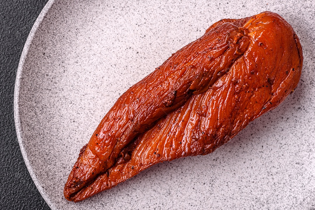 Delicioso peito de frango de carne defumada com sal, especiarias e ervas sobre um fundo escuro de concreto