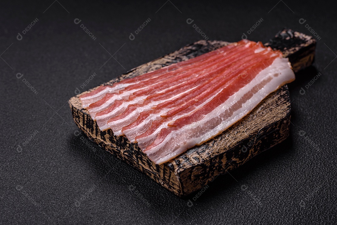 Delicioso bacon frito fresco com sal e especiarias sobre fundo escuro como ingrediente para preparar um farto café da manhã
