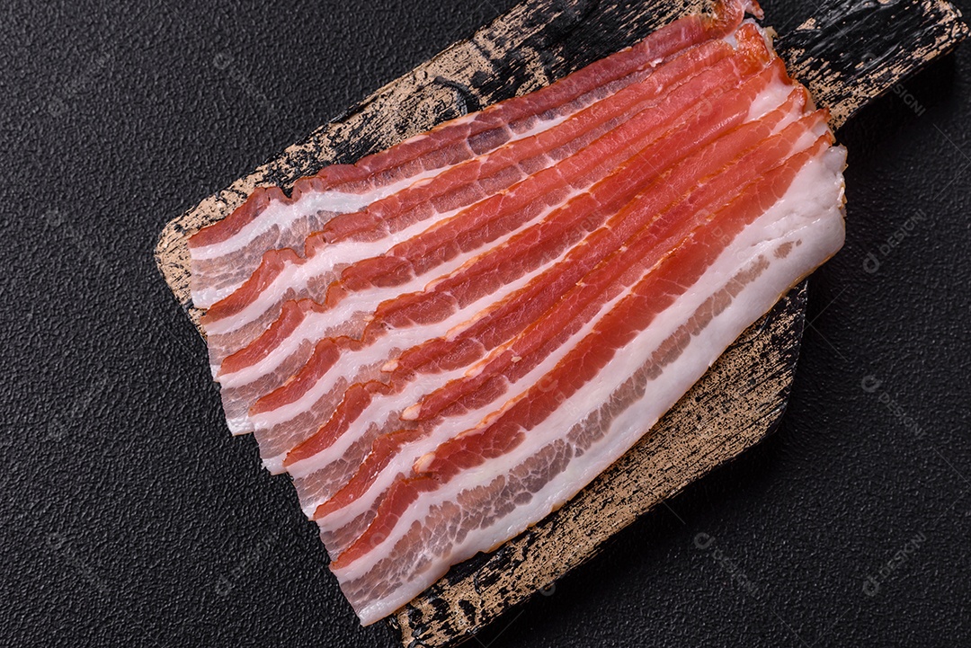 Delicioso bacon frito fresco com sal e especiarias sobre fundo escuro como ingrediente para preparar um farto café da manhã