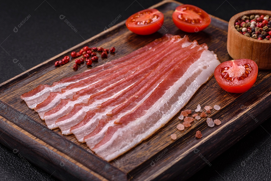 Delicioso bacon frito fresco com sal e especiarias sobre fundo escuro como ingrediente para preparar um farto café da manhã