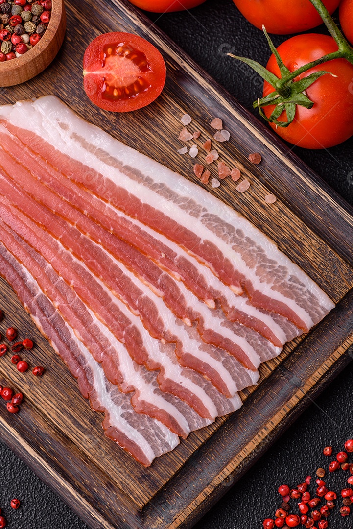 Delicioso bacon frito fresco com sal e especiarias sobre fundo escuro como ingrediente para preparar um farto café da manhã