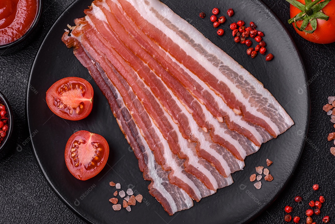 Delicioso bacon frito fresco com sal e especiarias sobre fundo escuro como ingrediente para preparar um farto café da manhã