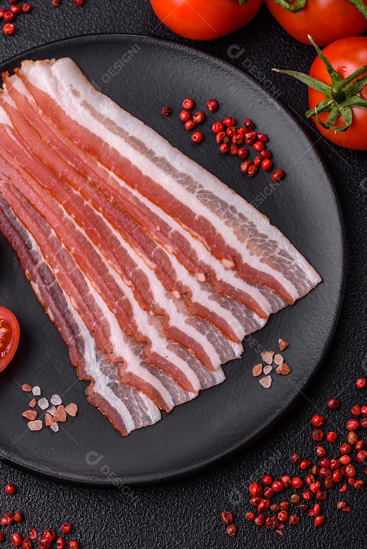 Delicioso bacon frito fresco com sal e especiarias sobre fundo escuro como ingrediente para preparar um farto café da manhã