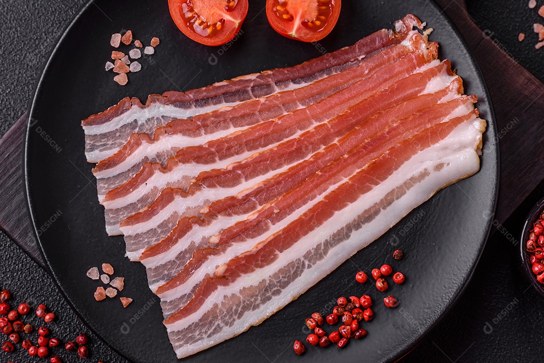 Delicioso bacon frito fresco com sal e especiarias sobre fundo escuro como ingrediente para preparar um farto café da manhã