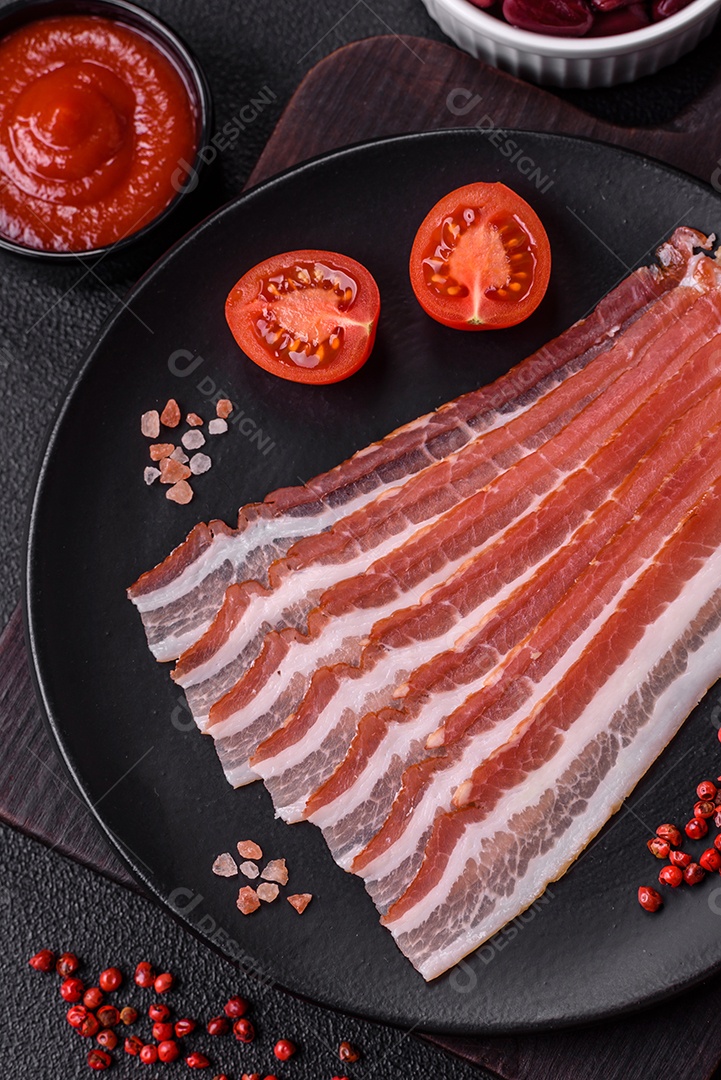 Delicioso bacon frito fresco com sal e especiarias sobre fundo escuro como ingrediente para preparar um farto café da manhã