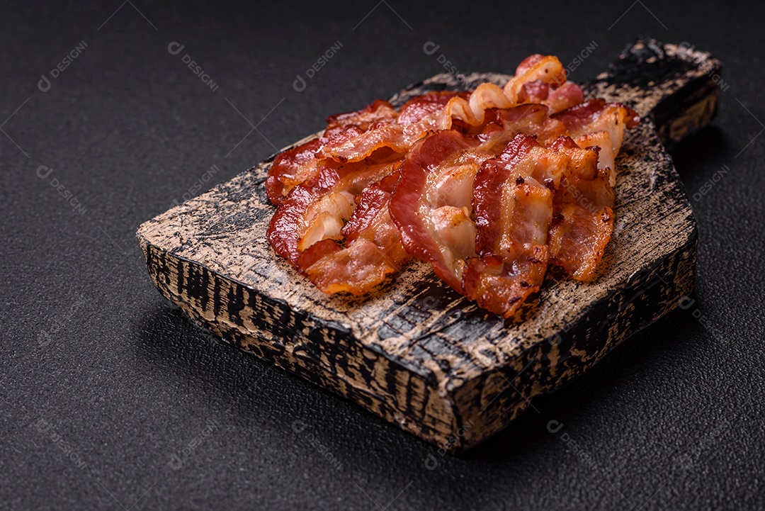 Delicioso bacon frito fresco com sal e especiarias sobre fundo escuro como ingrediente para preparar um farto café da manhã