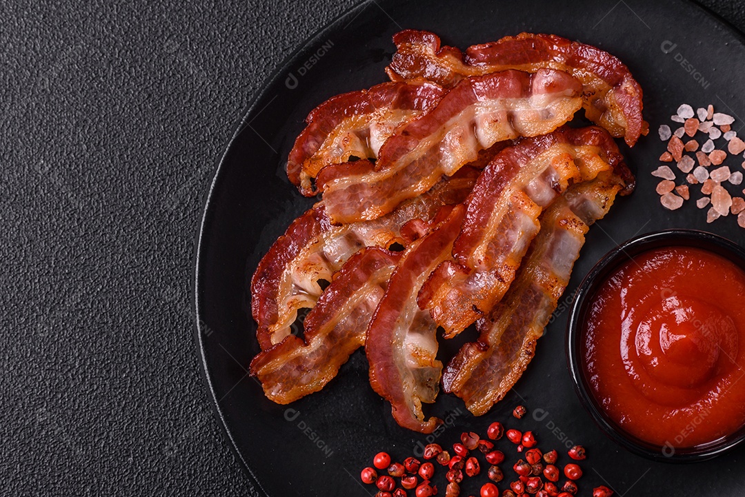 Delicioso bacon frito fresco com sal e especiarias sobre fundo escuro como ingrediente para preparar um farto café da manhã