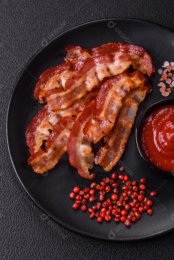 Delicioso bacon frito fresco com sal e especiarias sobre fundo escuro como ingrediente para preparar um farto café da manhã