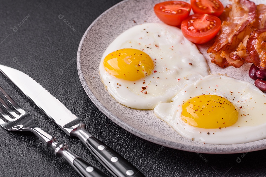 Café da manhã inglês com ovos fritos, bacon, feijão, tomate, especiarias e ervas. Um início de dia saudável e nutritivo