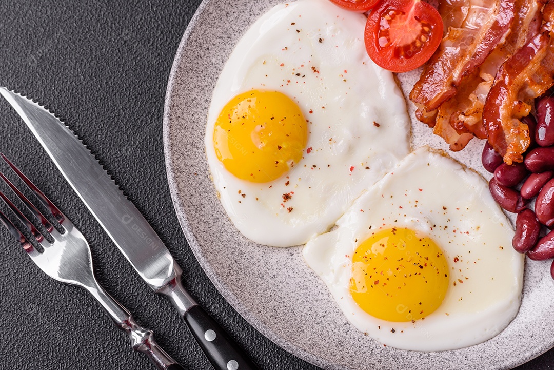 Café da manhã inglês com ovos fritos, bacon, feijão, tomate, especiarias e ervas. Um início de dia saudável e nutritivo