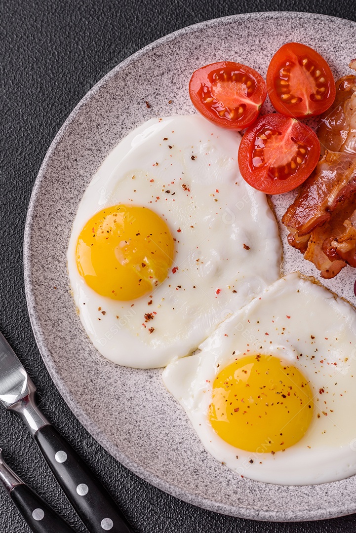 Café da manhã inglês com ovos fritos, bacon, feijão, tomate, especiarias e ervas. Um início de dia saudável e nutritivo
