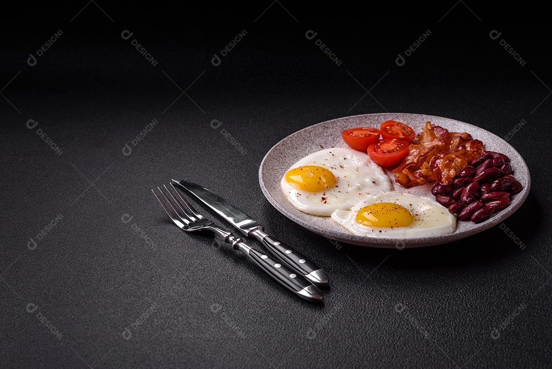 Café da manhã inglês com ovos fritos, bacon, feijão, tomate, especiarias e ervas. Um início de dia saudável e nutritivo