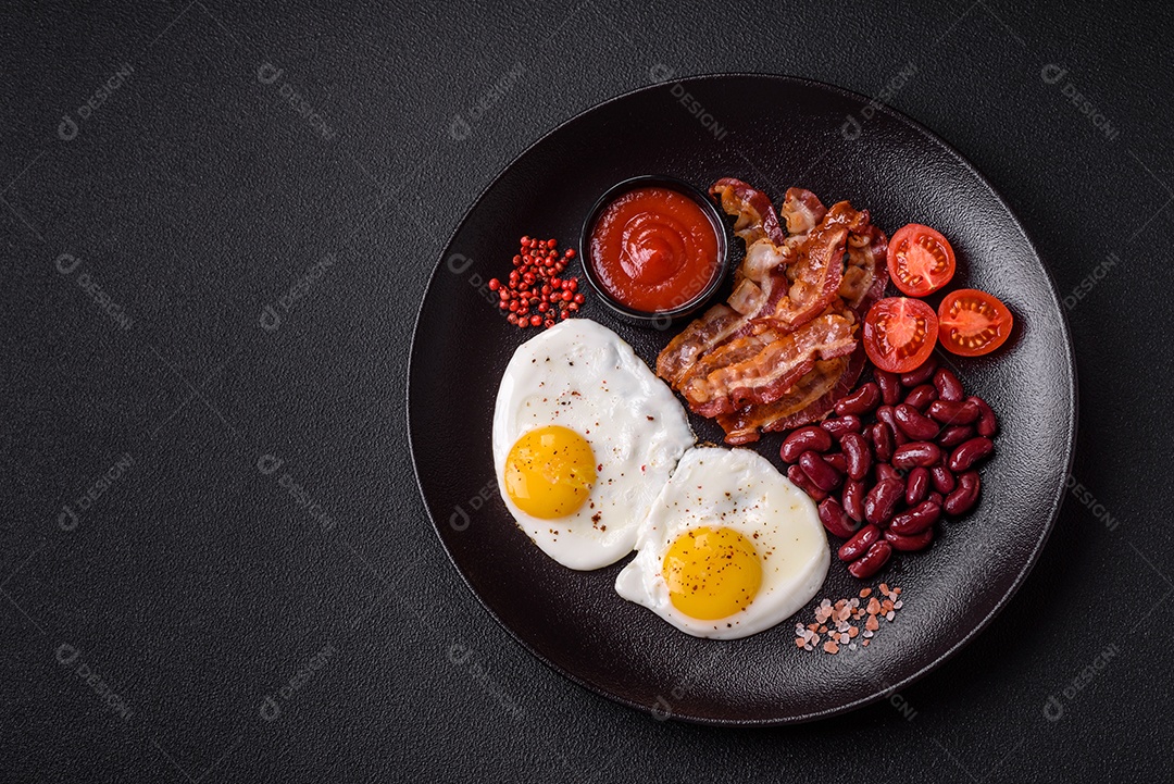 Café da manhã inglês com ovos fritos, bacon, feijão, tomate, especiarias e ervas. Um início de dia saudável e nutritivo