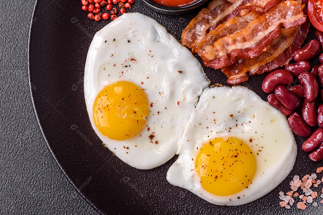 Café da manhã inglês com ovos fritos, bacon, feijão, tomate, especiarias e ervas. Um início de dia saudável e nutritivo