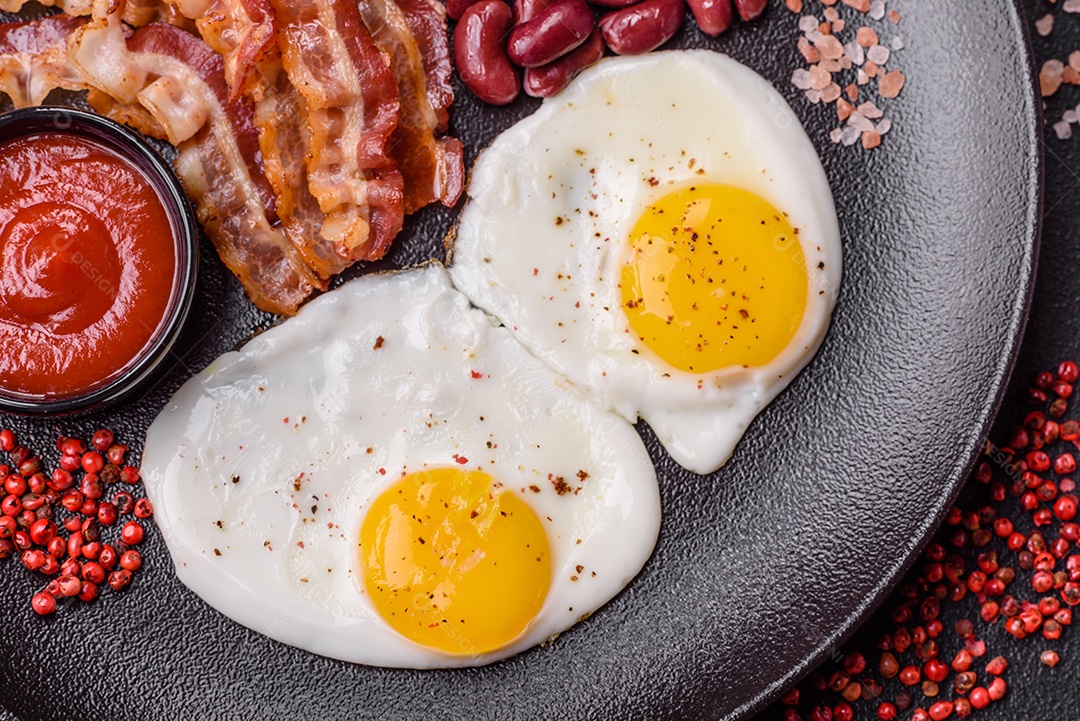 Café da manhã inglês com ovos fritos, bacon, feijão, tomate, especiarias e ervas. Um início de dia saudável e nutritivo
