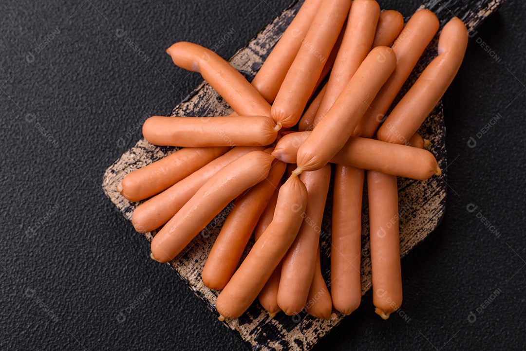 Deliciosas pequenas salsichas vegetarianas frescas com sal, especiarias e ervas sobre um fundo escuro de concreto