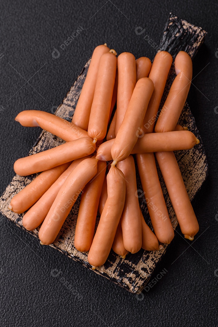 Deliciosas pequenas salsichas vegetarianas frescas com sal, especiarias e ervas sobre um fundo escuro de concreto