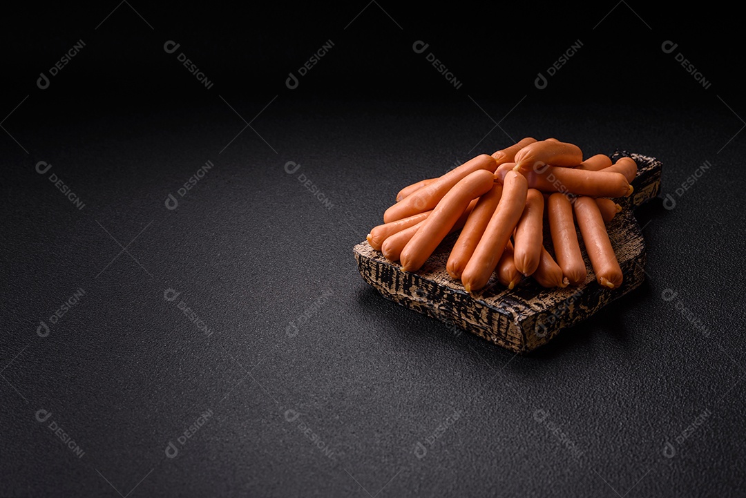 Deliciosas pequenas salsichas vegetarianas frescas com sal, especiarias e ervas sobre um fundo escuro de concreto