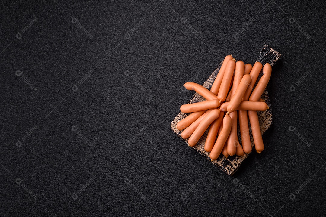 Deliciosas pequenas salsichas vegetarianas frescas com sal, especiarias e ervas sobre um fundo escuro de concreto