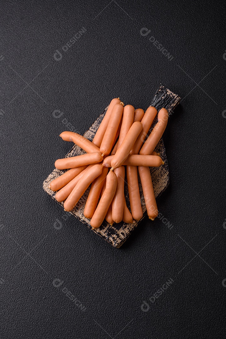 Deliciosas pequenas salsichas vegetarianas frescas com sal, especiarias e ervas sobre um fundo escuro de concreto