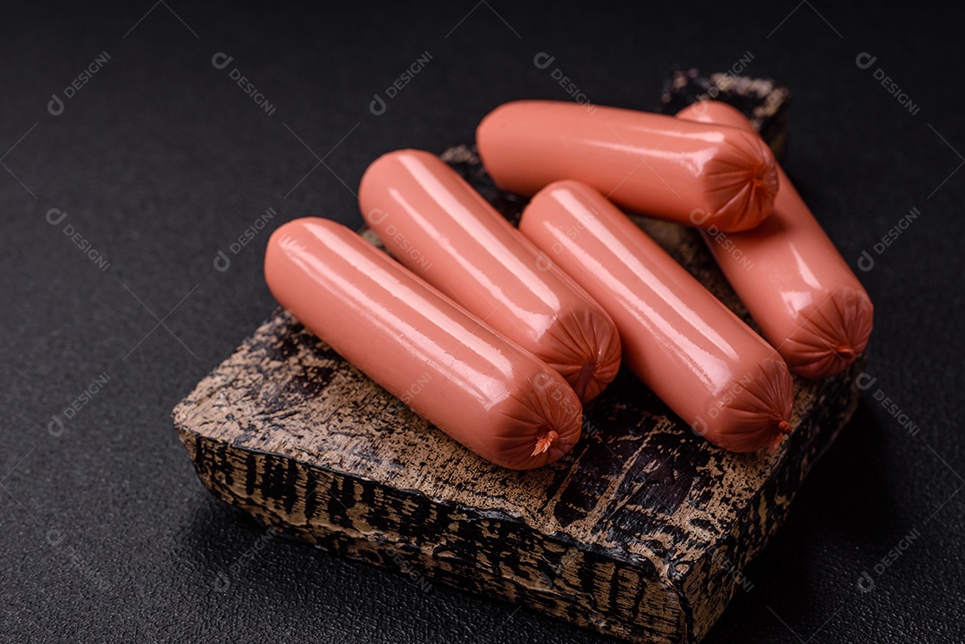 Deliciosas pequenas salsichas vegetarianas frescas com sal, especiarias e ervas sobre um fundo escuro de concreto