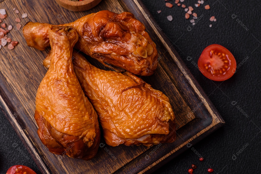 Deliciosas pernas de frango assadas na grelha com sal, especiarias e ervas sobre um fundo de concreto texturizado