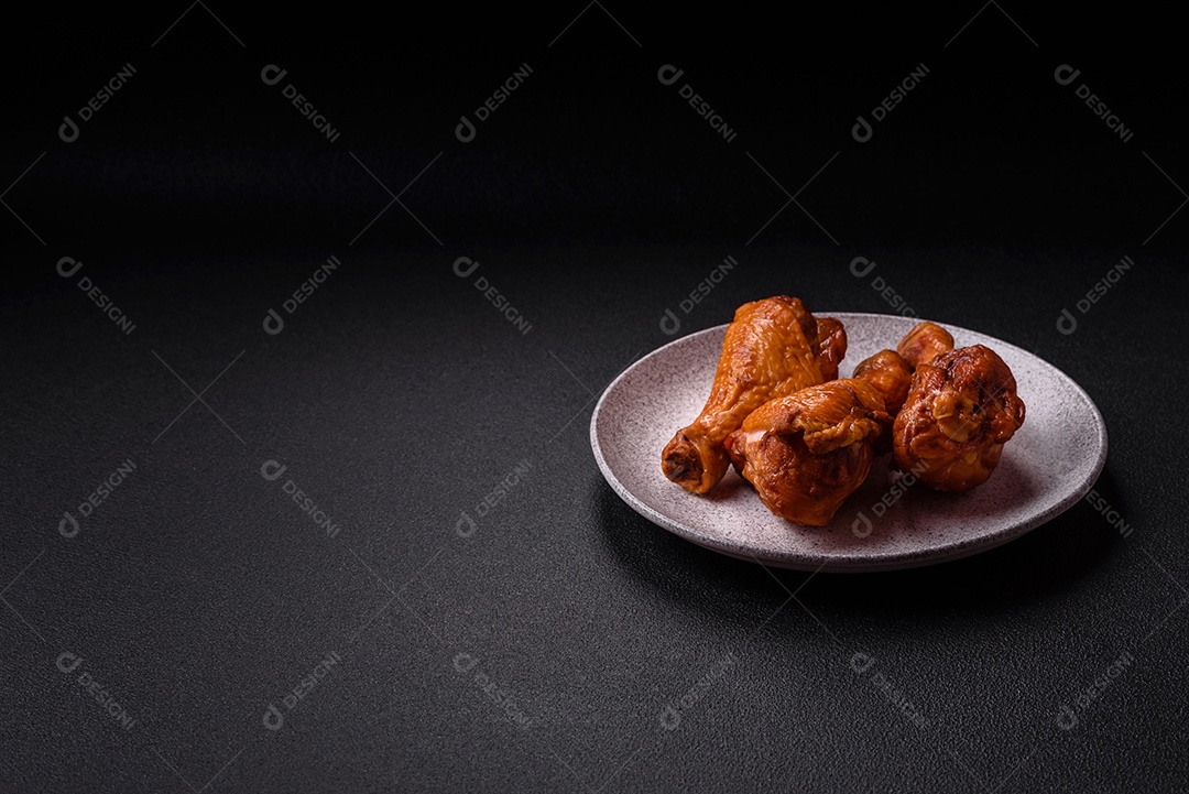 Deliciosas pernas de frango assadas na grelha com sal, especiarias e ervas sobre um fundo de concreto texturizado