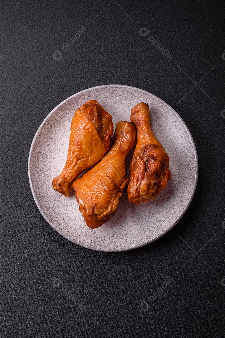 Deliciosas pernas de frango assadas na grelha com sal, especiarias e ervas sobre um fundo de concreto texturizado