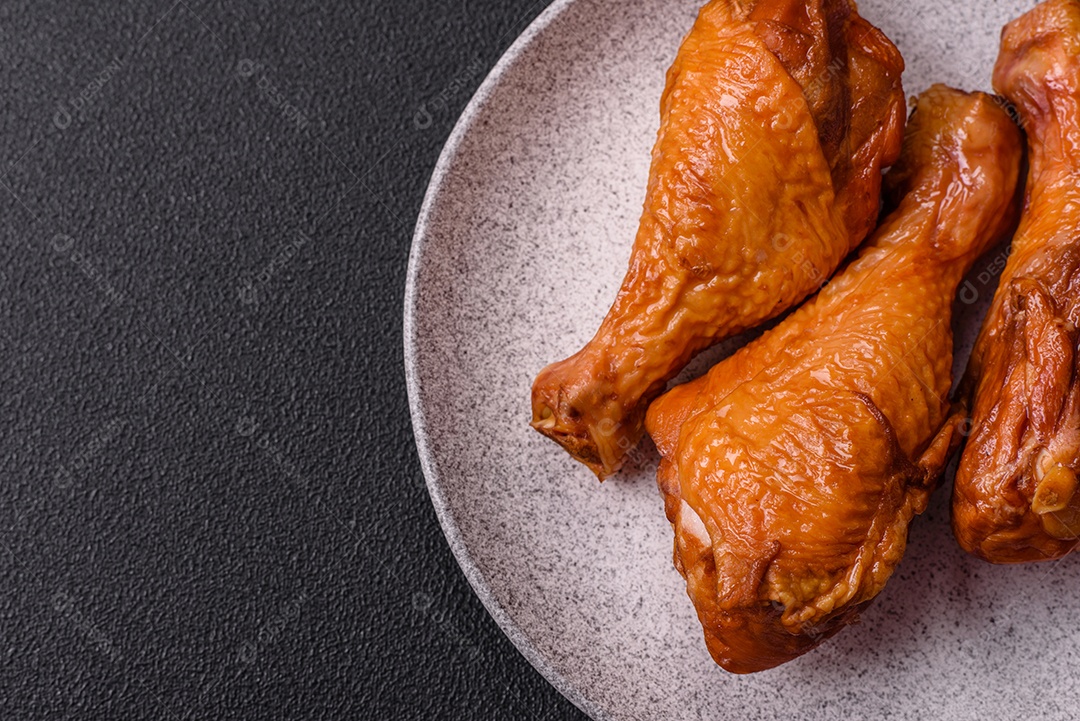 Deliciosas pernas de frango assadas na grelha com sal, especiarias e ervas sobre um fundo de concreto texturizado