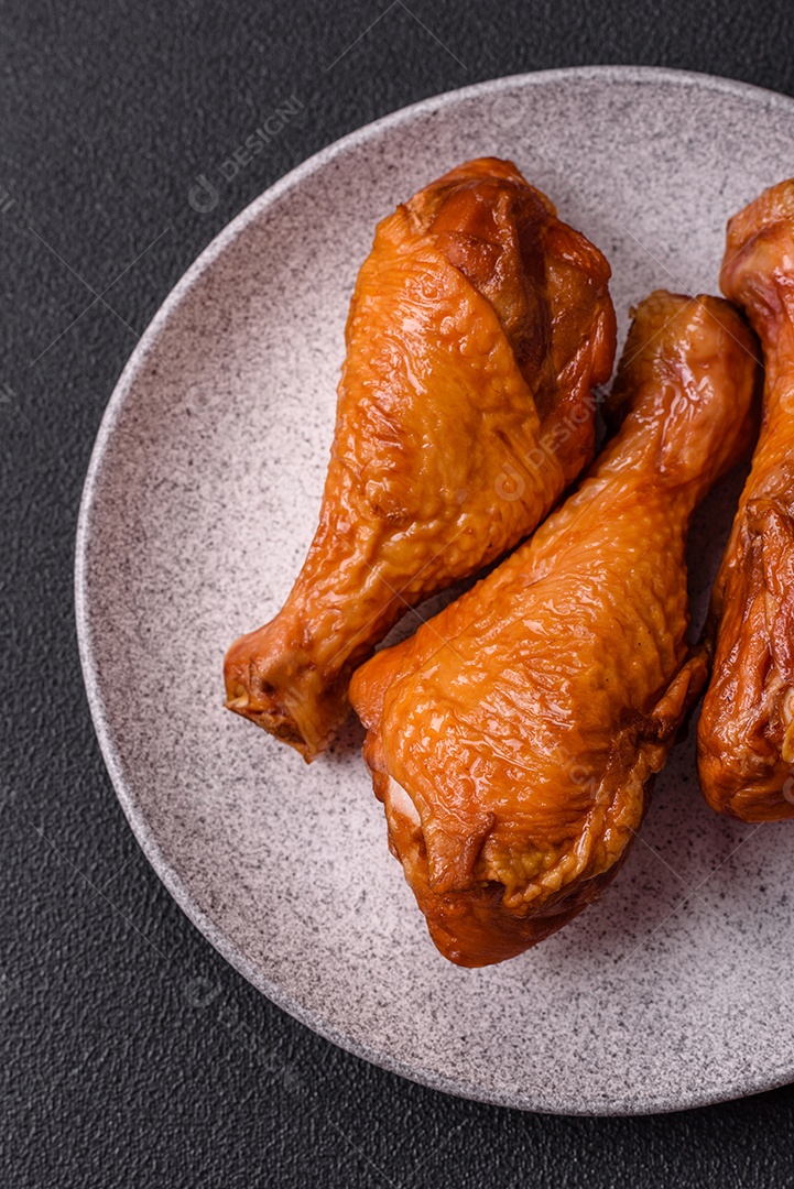 Deliciosas pernas de frango assadas na grelha com sal, especiarias e ervas sobre um fundo de concreto texturizado