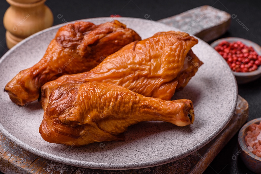 Deliciosas pernas de frango assadas na grelha com sal, especiarias e ervas sobre um fundo de concreto texturizado