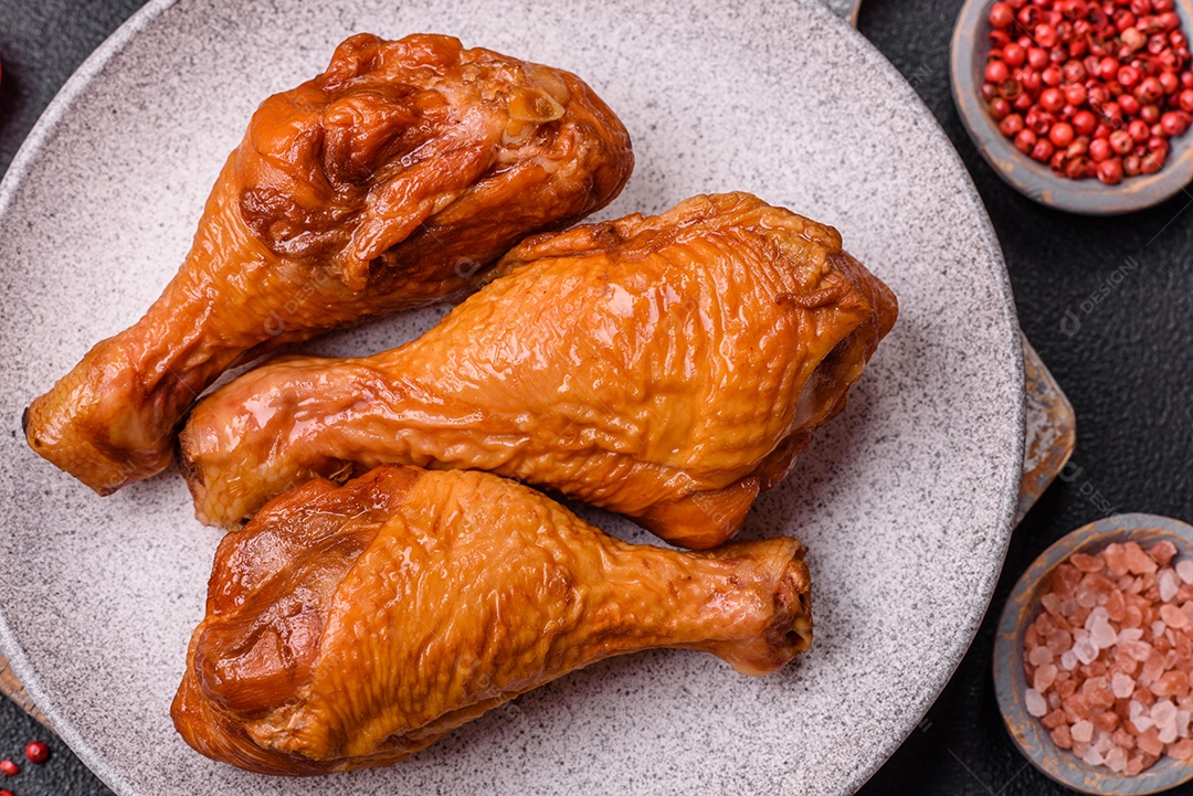 Deliciosas pernas de frango assadas na grelha com sal, especiarias e ervas sobre um fundo de concreto texturizado