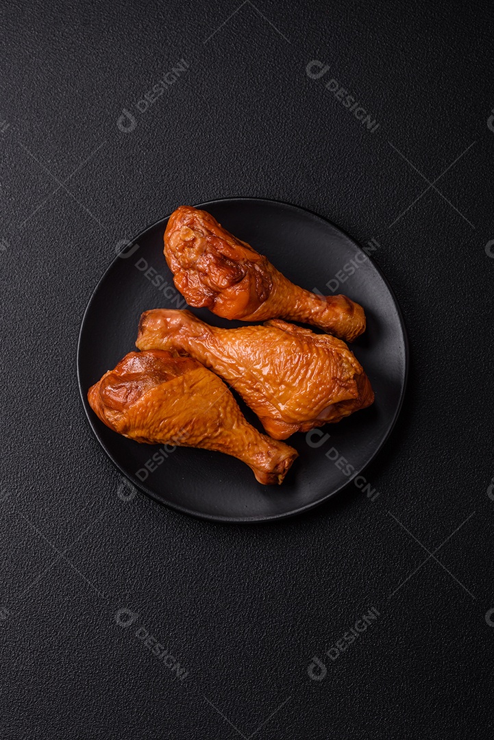 Deliciosas pernas de frango assadas na grelha com sal, especiarias e ervas sobre um fundo de concreto texturizado