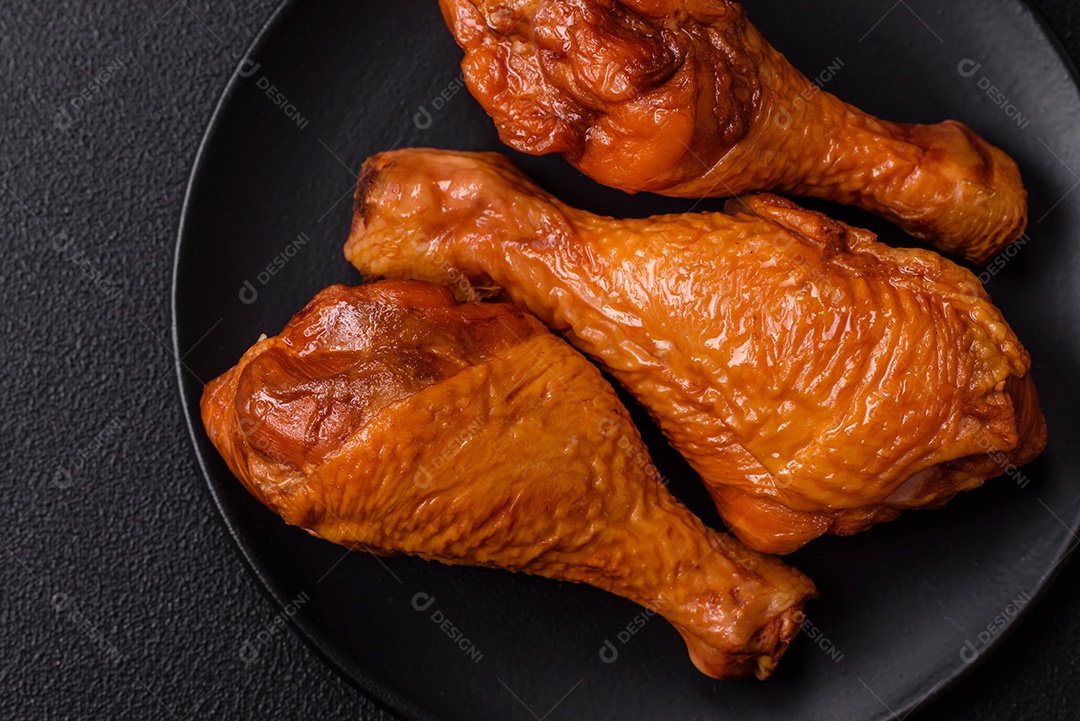 Deliciosas pernas de frango assadas na grelha com sal, especiarias e ervas sobre um fundo de concreto texturizado