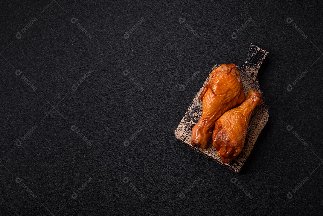 Deliciosas pernas de frango assadas na grelha com sal, especiarias e ervas sobre um fundo de concreto texturizado