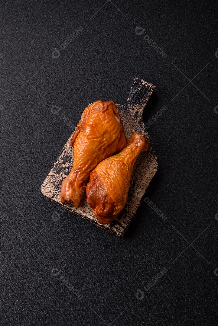 Deliciosas pernas de frango assadas na grelha com sal, especiarias e ervas sobre um fundo de concreto texturizado