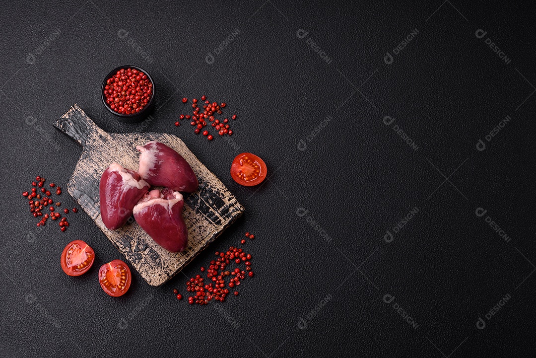 Corações crus de peru ou frango com sal e especiarias sobre um fundo escuro de concreto