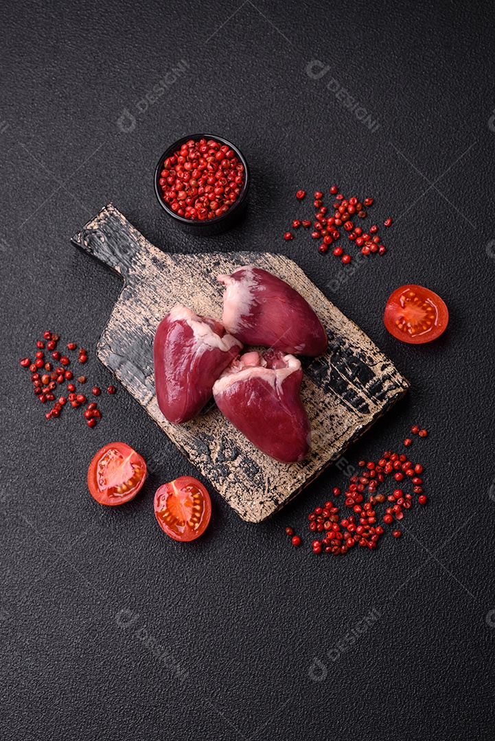 Corações crus de peru ou frango com sal e especiarias sobre um fundo escuro de concreto