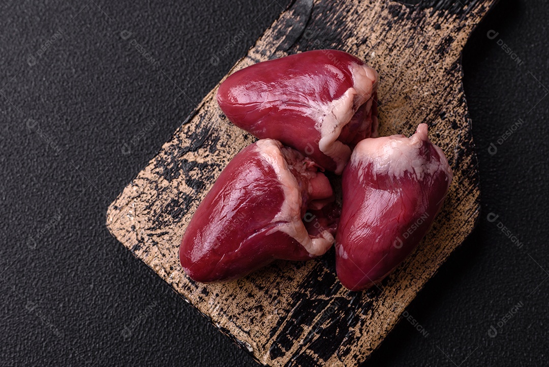 Corações crus de peru ou frango com sal e especiarias sobre um fundo escuro de concreto