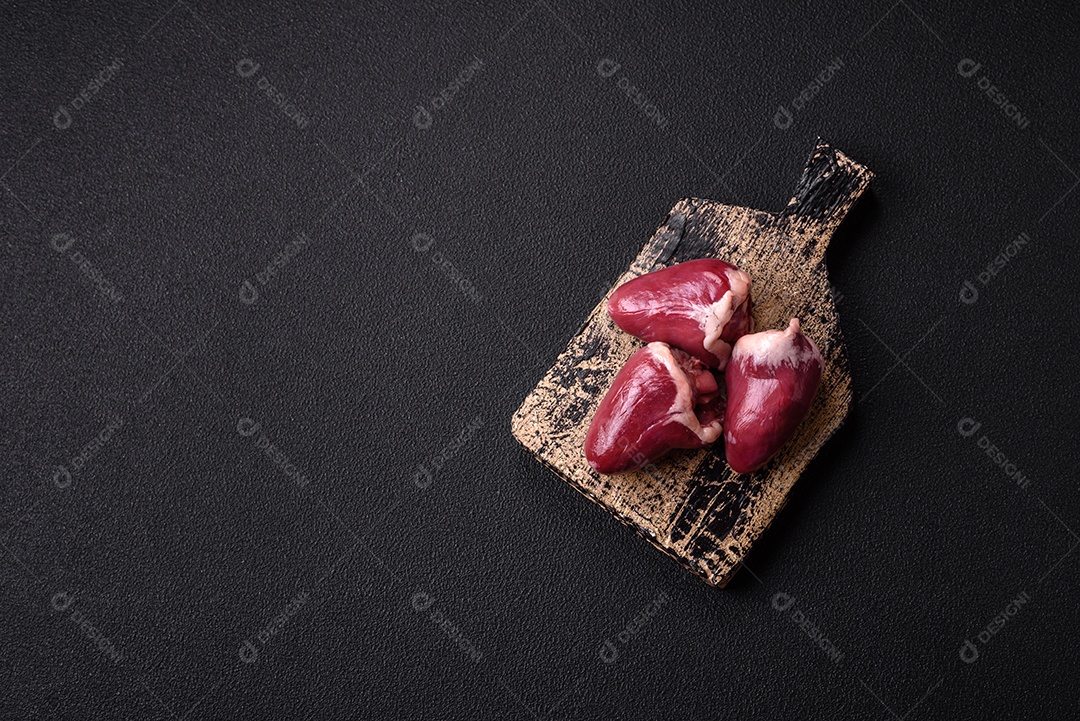 Corações crus de peru ou frango com sal e especiarias sobre um fundo escuro de concreto