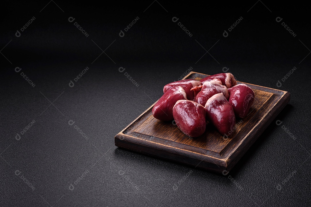 Corações crus de peru ou frango com sal e especiarias sobre um fundo escuro de concreto