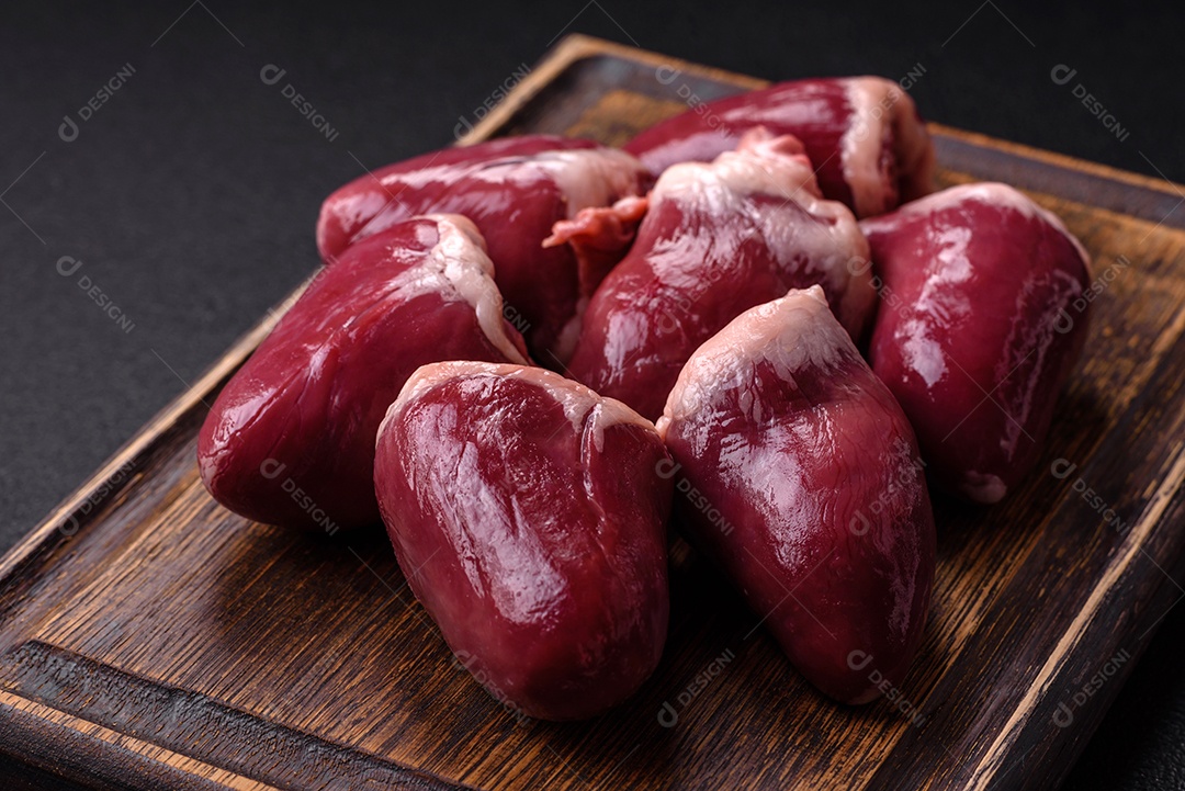 Corações crus de peru ou frango com sal e especiarias sobre um fundo escuro de concreto