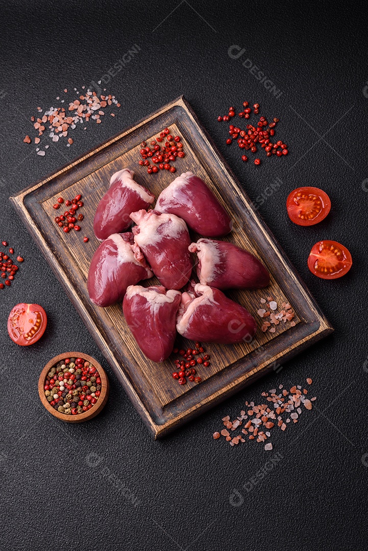 Corações crus de peru ou frango com sal e especiarias sobre um fundo escuro de concreto